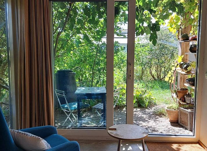 Aussenterrasse des Ferienhauses in Olst, Overijssel mit gruener Umgebung und blauen Gartenmoebeln.