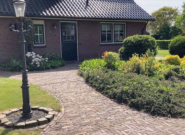 Gemuetliche Kueche in Cottage in Hellendoorn, Ferienhaus in Hellendoorn, Overijssel mit Holztisch und rosa Stuehlen.