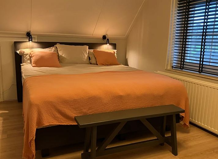 Gemuetliche Kueche in Cottage in Hellendoorn, Ferienhaus in Hellendoorn, Overijssel mit Holztisch und rosa Stuehlen.