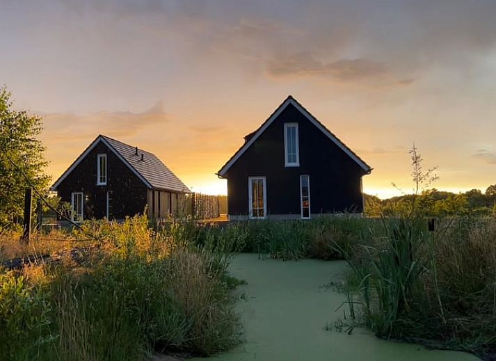 Vakantiehuis in Hellendoorn bij zonsondergang, omgeven door weelderige natuur in Salland, Overijssel.