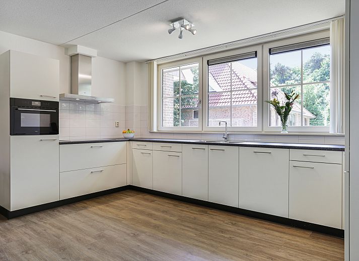 Eine Flasche Wein auf dem Tisch im Wohnzimmer des 12-Bett-Bungalows Landgoed De Hellendoornse Berg, Haarle, Overijssel fuer einen entspannten Aufenthalt.