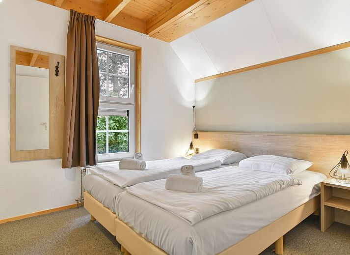 Gezellige woonkamer in Landgoed De Hellendoornse Berg bungalow, Haarle, met uitzicht op de tuin.