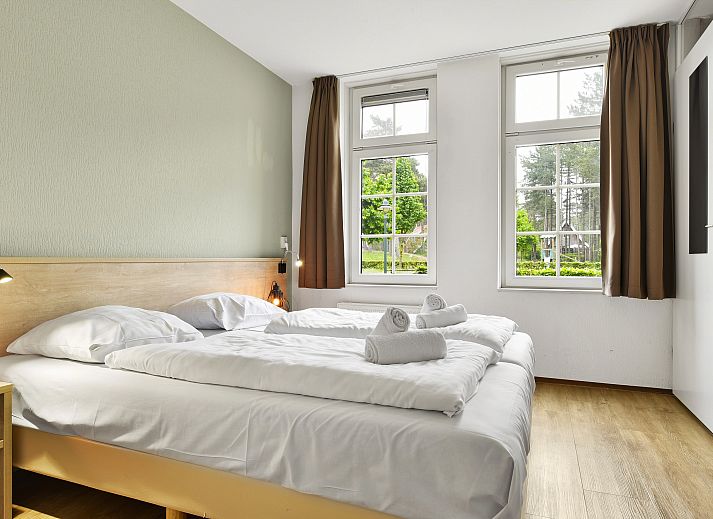 Ruime woonkamer met houten balken in 6-persoons bungalow op Landgoed De Hellendoornse Berg, Haarle.