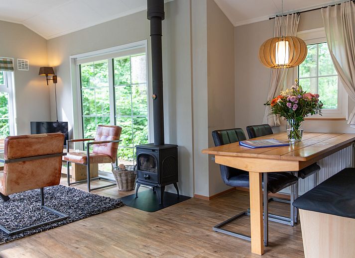 Geraeumiges Esszimmer im Ferienhaus 4-Bett-Wald in Dalfsen, mit einem grossen Holztisch und Blick auf den Garten in der Region Vecht, Overijssel.