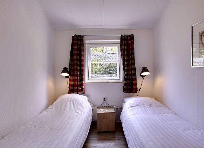 Geraeumiges Esszimmer im Ferienhaus 4-Bett-Wald in Dalfsen, mit einem grossen Holztisch und Blick auf den Garten in der Region Vecht, Overijssel.