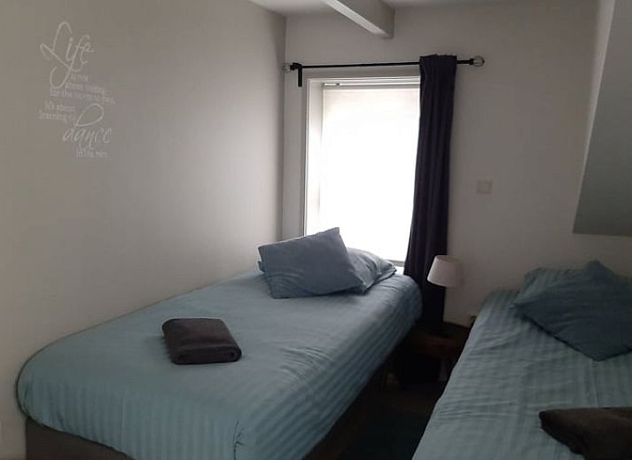 Gemuetliches Wohnzimmer von Huisje in Balkbrug, Ferienhaus in Vechtstreek, Overijssel, mit bequemen Ledersofas und Holzinterieur.