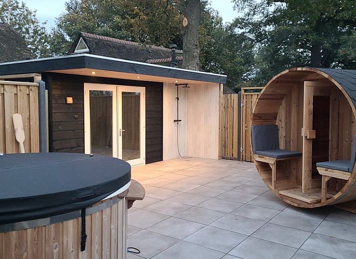 Entspannen Sie sich auf der Terrasse des Ferienhauses in Balkbrug, Vechtstreek, mit Sauna und bequemen Liegestuehlen, im gruenen Overijssel.