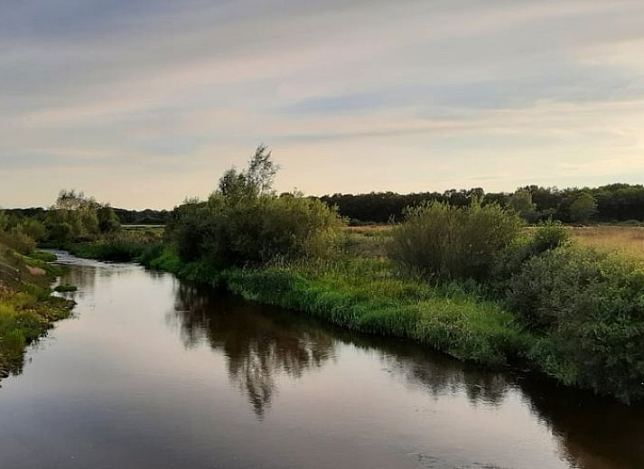 Gemuetliches Wohnzimmer des Ferienhauses in Stegeren, umgeben von Natur in der Region Vecht, Overijssel, mit grossem Fenster und bequemer Sitzecke.