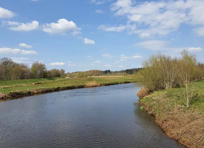 Gemuetliches Wohnzimmer des Ferienhauses in Stegeren, umgeben von Natur in der Region Vecht, Overijssel, mit grossem Fenster und bequemer Sitzecke.