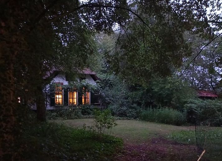Sfeervol verlicht vakantiehuis in Brucht, Vechtstreek, Overijssel in de avondschemering.