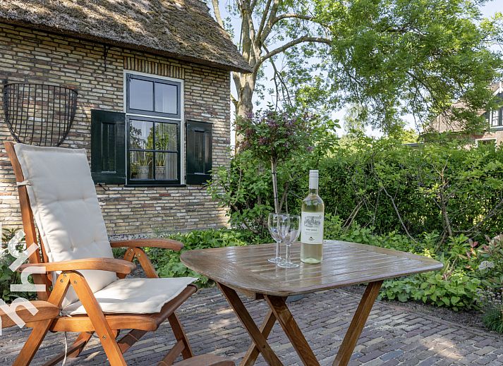 Rustieke tuin van OV553 vakantiehuis in Giethoorn met zitje en groene omgeving voor ontspanning.
