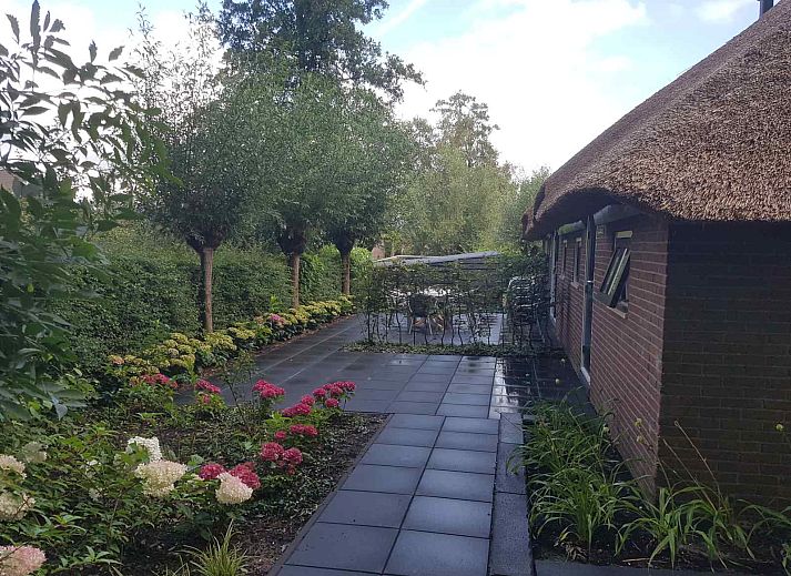 Attractive garden of vacation home OV601 in Giethoorn, Overijssel, with colorful flowers and paved path.