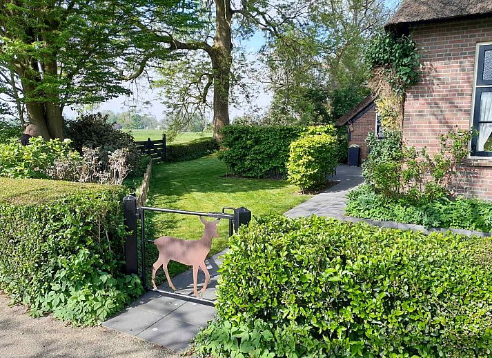Attractive garden of vacation home OV601 in Giethoorn, Overijssel, with colorful flowers and paved path.