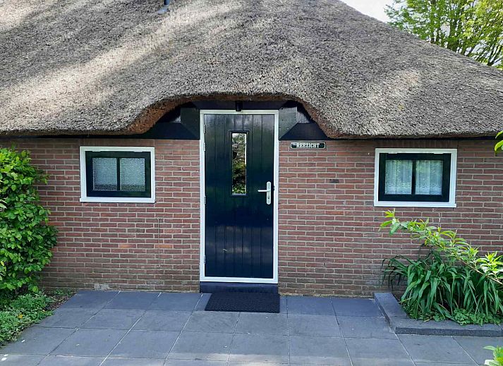 Entrance to vacation home OV601 in Giethoorn, surrounded by lush green hedges and trees.