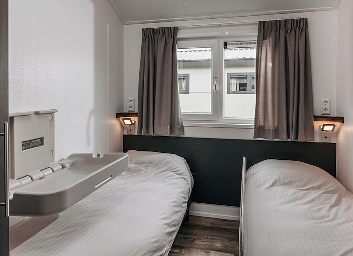 Moderne Kueche im Chalet Ooievaar 4, Giethoorn, Overijssel, mit eleganten schwarzen Schraenken und Blick auf die natuerliche Umgebung.