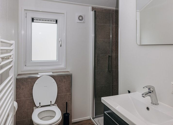 Moderne Kueche im Chalet Ooievaar 4, Giethoorn, Overijssel, mit eleganten schwarzen Schraenken und Blick auf die natuerliche Umgebung.