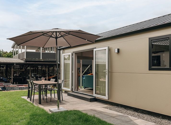 Moderne Kueche im Chalet Ooievaar 4, Giethoorn, Overijssel, mit eleganten schwarzen Schraenken und Blick auf die natuerliche Umgebung.