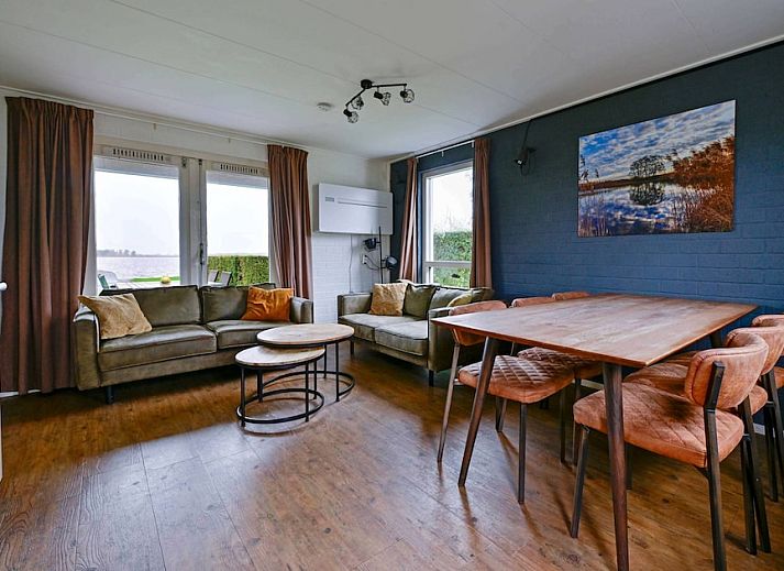 De Wijde Blik 6, ein komfortabler Bungalow in Giethoorn, Overijssel, mit einer schoenen Terrasse am Wasser und einer gruenen Umgebung.