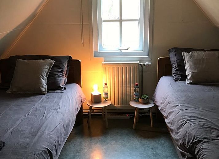 Ruhiges Wasser im Ferienhaus in Giethoorn, einem schoenen Ferienhaus in Overijssel, mit einer Holzbruecke und bunten Kissen.