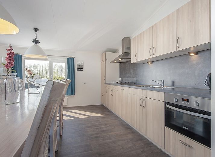 Ruime eetkamer in vakantiehuis Kraaiennest 12, Giethoorn, met lange tafel en moderne keuken in Noordwest Overijssel, Overijssel.