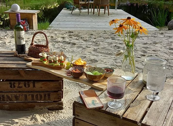 Relax on the sandy beach at Holiday Home in De Bult, Overijssel, overlooking a serene pond and green surroundings.