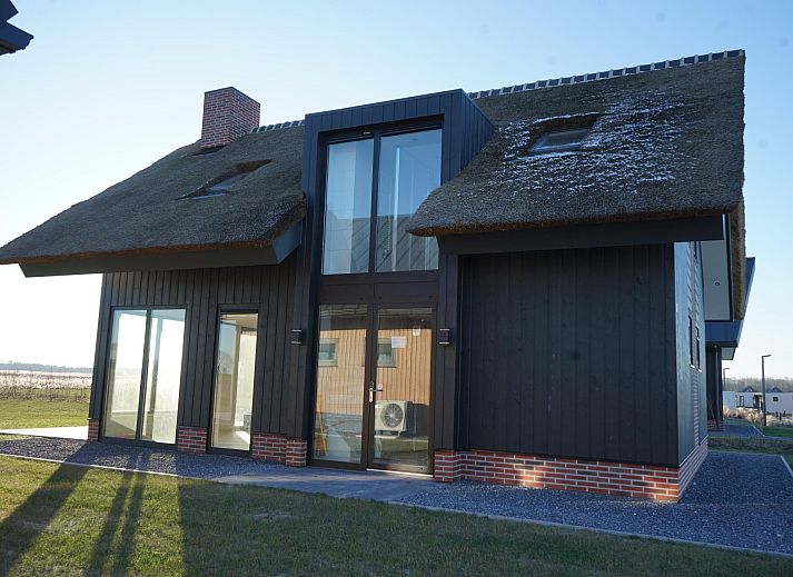 Vrijstaande woning in Kampen, een vakantiehuis in Noordwest Overijssel, met moderne architectuur en rieten dak, omringd door natuur.