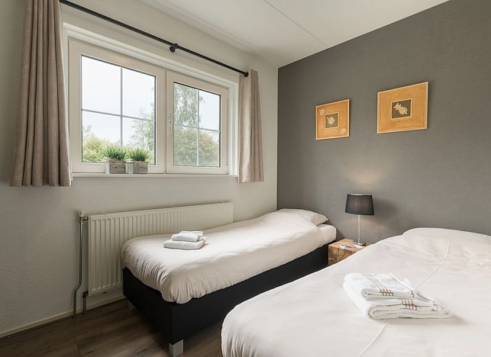 Gemuetliches Wohnzimmer im Ferienhaus Karekiet 8 in Paasloo, Overijssel, mit geraeumiger Sitzecke und Blick auf die gruene Umgebung.