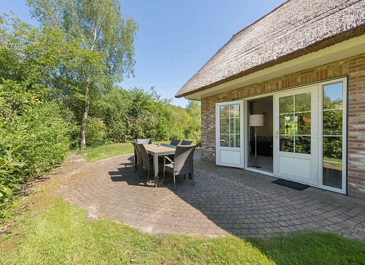 Gemuetliches Wohnzimmer im Ferienhaus Karekiet 8 in Paasloo, Overijssel, mit geraeumiger Sitzecke und Blick auf die gruene Umgebung.