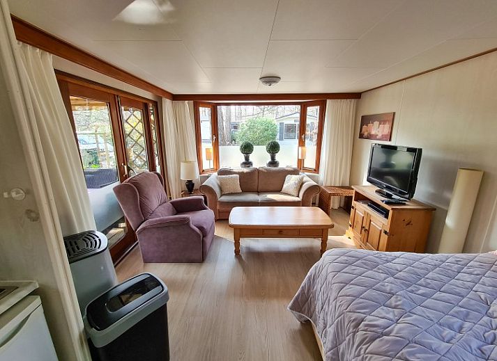 Sfeervolle toegangspoort naar Chalet Boslust in IJhorst, omgeven door bloeiende flora in Overijssel.