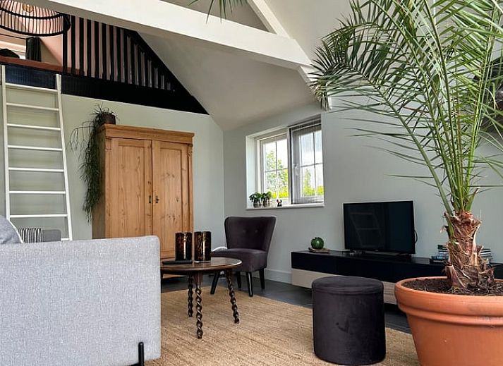 Lichte woonkamer van Vakantiehuis in Kalenberg, Overijssel, met grote ramen en uitzicht op de groene omgeving.