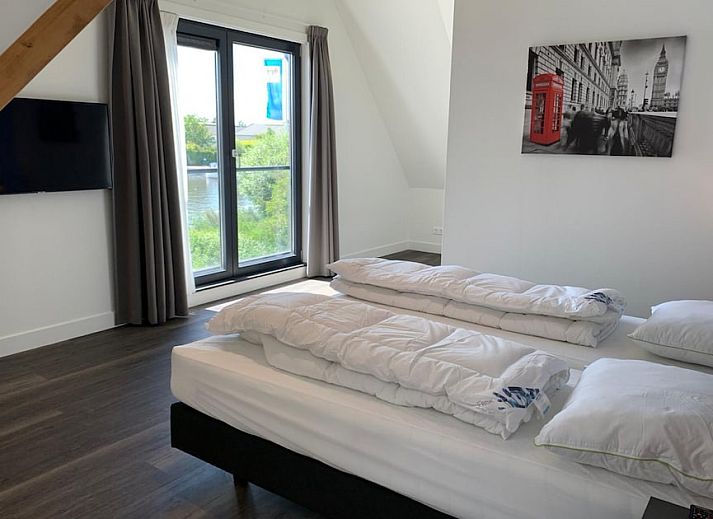 Family Villa 12 in Ossenzijl, Overijssel, a charming vacation home with thatched roof and waterfront terrace for a relaxing stay.