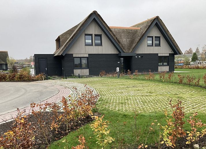 Family Villa 12 in Ossenzijl, Overijssel, a charming vacation home with thatched roof and waterfront terrace for a relaxing stay.