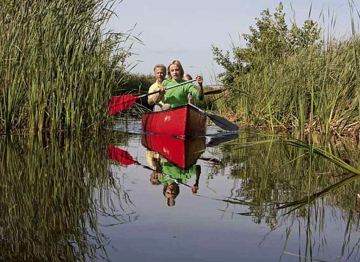 Gezellige woonkamer van OV400 vakantiehuis in Ossenzijl met houtkachel en uitzicht op de natuur.