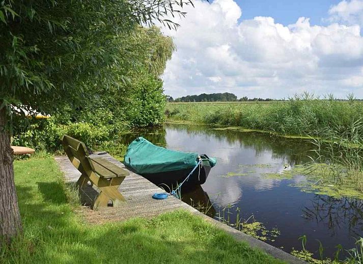 Gezellige woonkamer van OV400 vakantiehuis in Ossenzijl met houtkachel en uitzicht op de natuur.