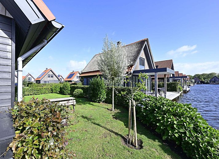 Moderne woonkamer met grote ramen in de vakantiewoning in Ossenzijl, Overijssel, met uitzicht op de tuin.