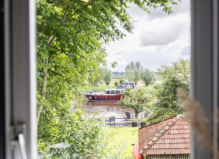 Sfeervolle slaapkamer in Vakantiehuisje in Wetering, Overijssel. Comfortabel bed onder een dakraam.