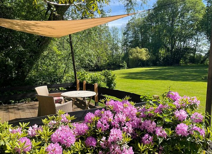 Gezellig terras bij Huisje in Tienhoven, vakantiehuis in Tienhoven, Utrecht, met uitzicht op groene tuin en bloemen.