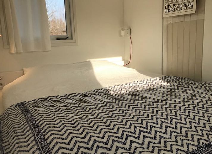 Gezellige zithoek in Vakantiehuisje in Tienhoven, Utrecht noord, met oranje bank en uitzicht op de natuur.