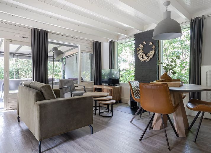 Entspannen Sie sich auf der ueberdachten Veranda des Bungalows Schoonoord in Doorn, Utrechtse Heuvelrug, mit Blick auf die gruene Umgebung.