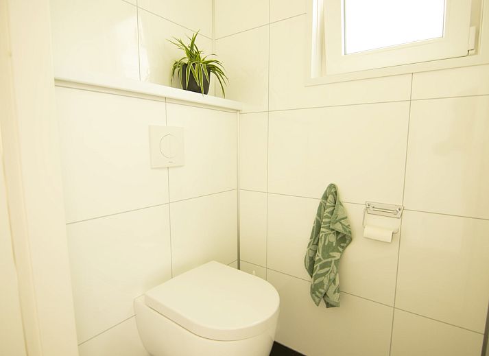 Gemuetliches Wohnzimmer des Bungalows Zuylestein in Doorn mit komfortablen Moebeln und Blick auf die Natur.