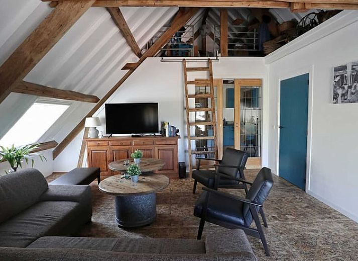 Gezellige woonkamer in Vakantiehuisje in Achterveld, Utrechtse Heuvelrug, met houten balken en comfortabele zitruimte.