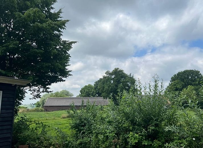 Blick vom Ferienhaus in Stoutenburg auf eine gruene Wiese und einen Bauernhof in Utrecht.