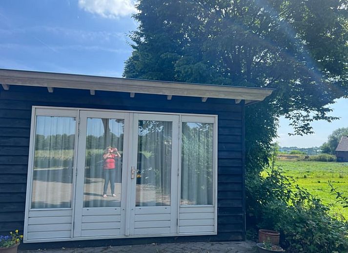 Blick vom Ferienhaus in Stoutenburg auf eine gruene Wiese und einen Bauernhof in Utrecht.