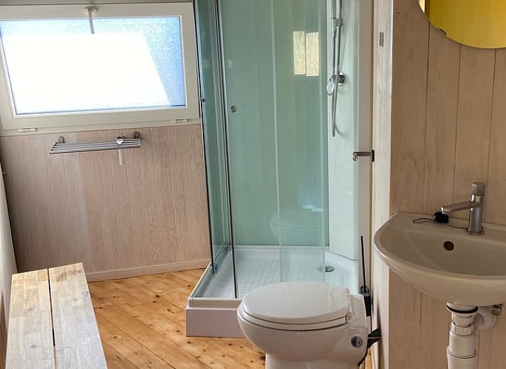 Cozy indoor area of Huisje in IJsselstein, vacation home located in Utrecht, with comfortable yellow armchairs and water views.