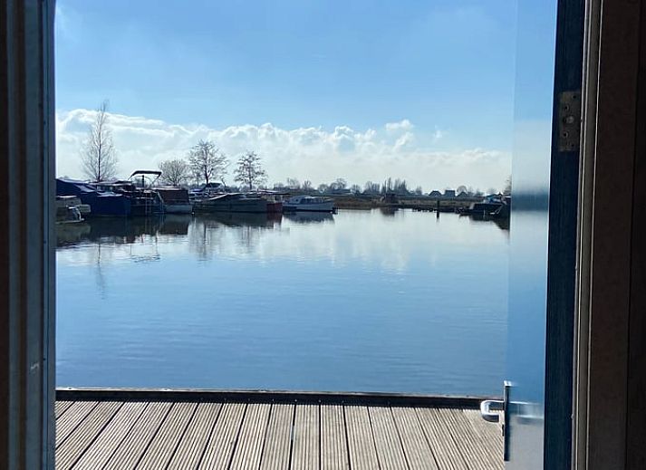 Cozy indoor area of Huisje in IJsselstein, vacation home located in Utrecht, with comfortable yellow armchairs and water views.