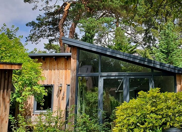 Vakantiehuisje in Bilthoven met moderne glazen gevel in Utrecht, omgeven door groen.