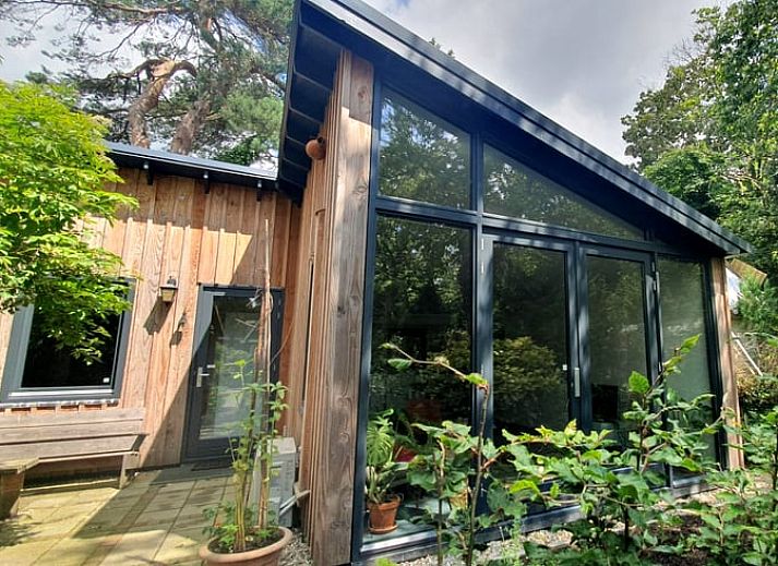 Vakantiehuisje in Bilthoven met moderne glazen gevel in Utrecht, omgeven door groen.