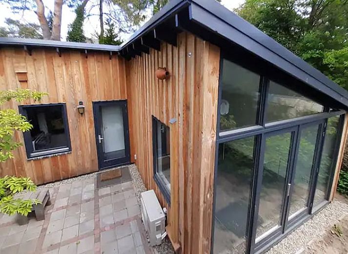 Vakantiehuisje in Bilthoven met moderne glazen gevel in Utrecht, omgeven door groen.