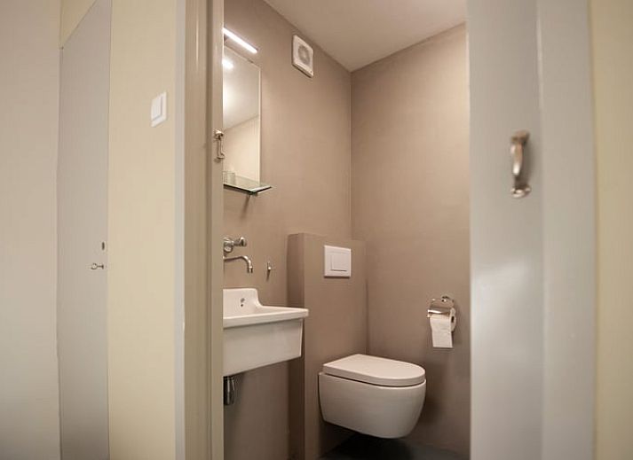 Schaduwrijke patio bij Vakantiehuisje in Bilthoven, Utrecht, met houten bank.