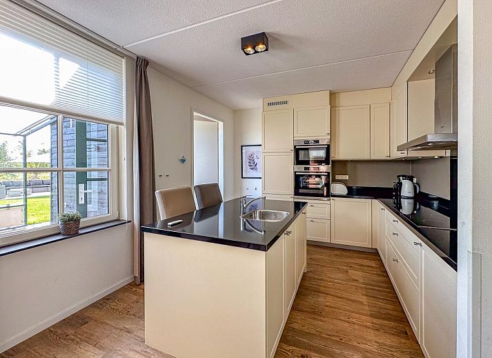 Ruim grasveld met trampoline bij vakantiehuis Dune Design 39 in Colijnsplaat, Noord-Beveland, Zeeland, omgeven door zonnige tuinen.